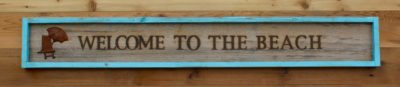Branded wall sign Welcome To The Beach with a finding glued on the right side.